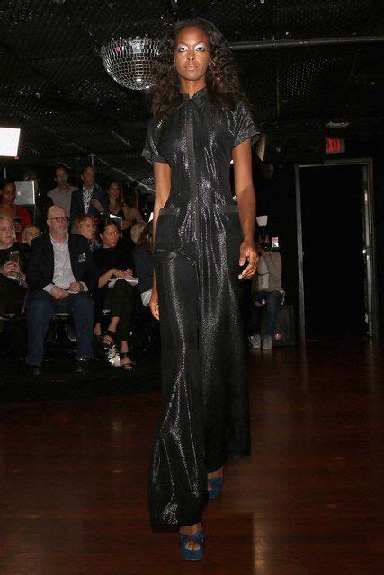 A Woman Is Walking Down The Runway At A Fashion Show