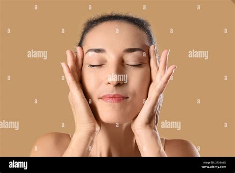 Beautiful Mature Woman Giving Herself Face Massage On Beige Background Stock Photo Alamy