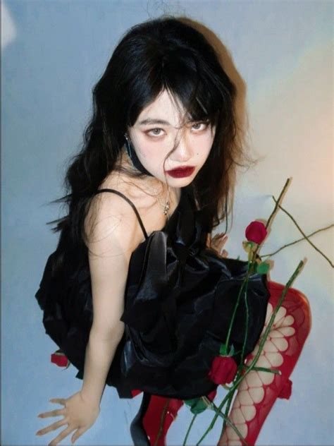 A Doll With Long Black Hair And Red Lips Holding A Rose In Her Hand