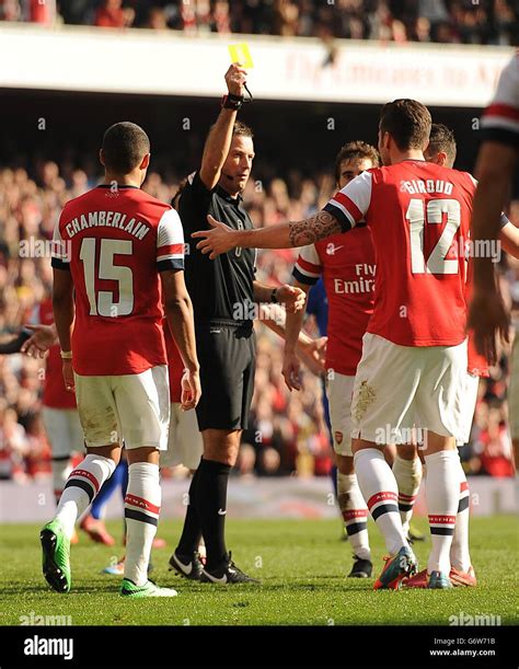 Referee Mark Clattenburg Shows A Yellow Card To Arsenal S Olivier