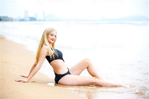 belle femme blonde en bikini noir profiter de l été sur la plage Photo de stock chez