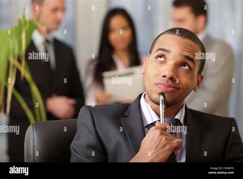 Pensive African American Businessman With His Team Working Behind Stock