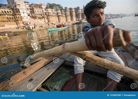 Boatmen On A Boat Glides Through Water On Ganges River Along Shore Of