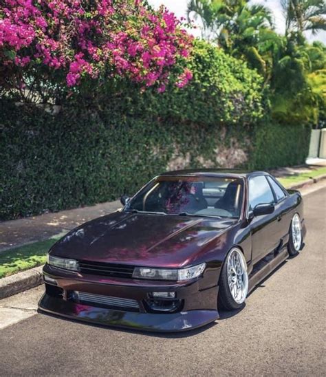 A Purple Car Parked On The Side Of A Road Next To Bushes And Trees With