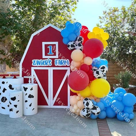 A Bunch Of Balloons Are In Front Of A Red Barn With A Cow Print On It