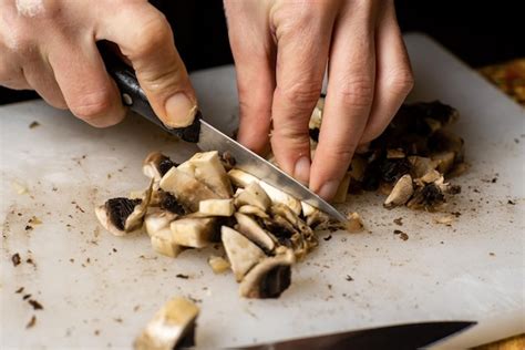 Champiñones en rodajas en una tabla de cortar las manos de las mujeres