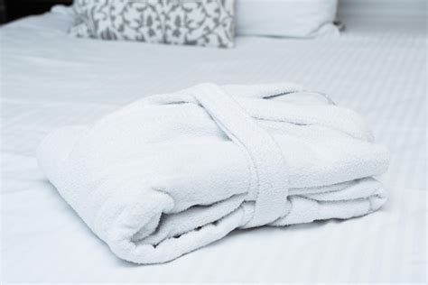 Premium Photo | White hotel bathrobe on bedroom bed