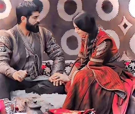 A Man And Woman Sitting On Top Of A Bed In Front Of A Wall With Circles