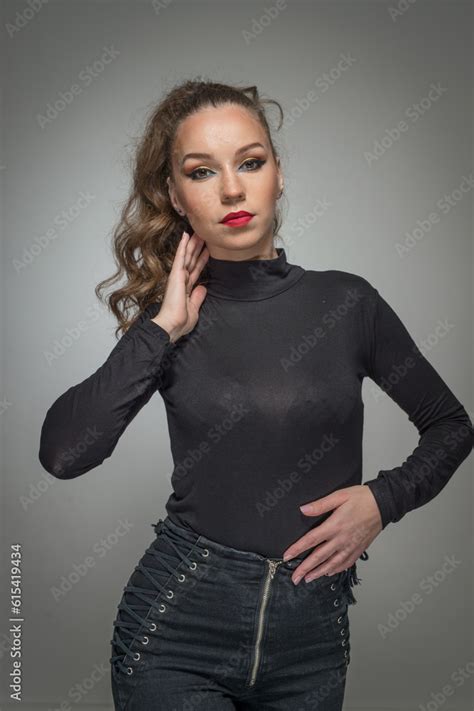 Attractive Woman In Black Blouse And Red Lips Posing Challenging In Front Of A Background