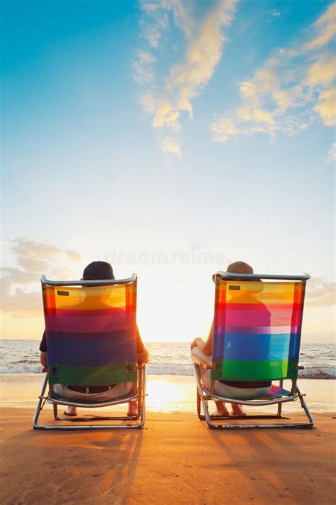 Romantic Couple On Deckchair Relaxing Enjoying Sunset On The Beach