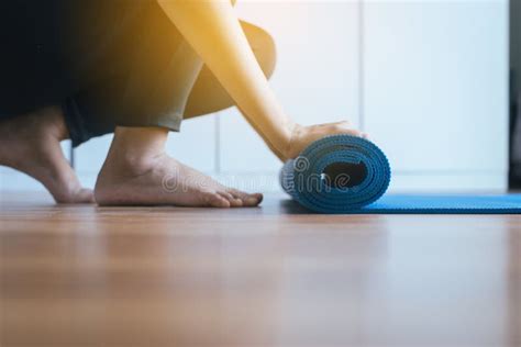 Close Up Of Hand Woman Rolling Or Folding Blue Yoga Mat After A Workout