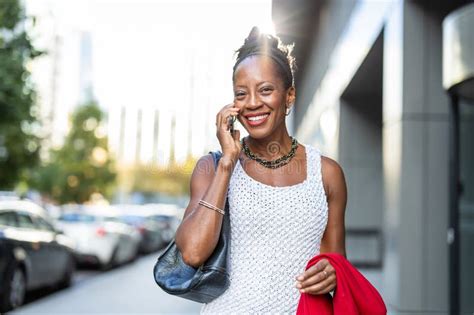 Smiling Mature Businesswoman Using Mobile Phone In Urban Setting Stock