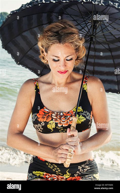 A Woman In A Bathing Suit Standing On The Beach With A Vintage