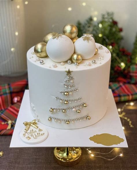 A White Cake Decorated With Gold Ornaments And Baubles On Top Of A Card