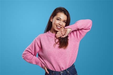 Positive Young Woman In Pink Sweater Standing With Hand On Hip And