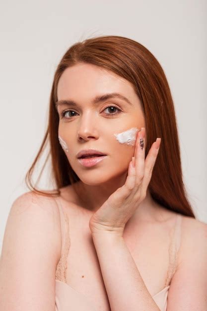 Premium Photo Beautiful Young Happy Redhead Fresh Lady Applying Moisturizer Cream On Face Skin