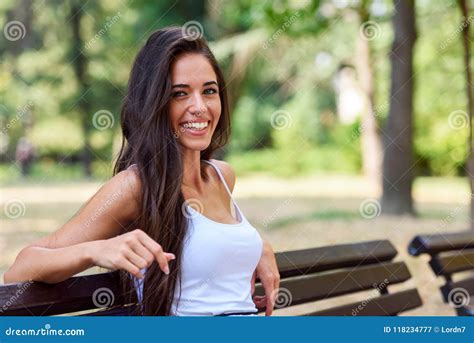 Portrait Of Young Beautiful Woman Sitting On Bench In The Public Park