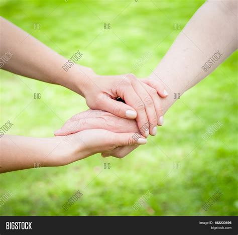 Young hands holding old age hands in front of green background Stock ...