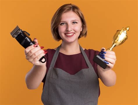 Peluquería de mujer hermosa joven en delantal con máquina recortadora y