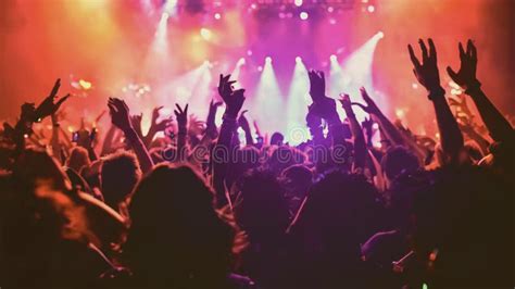 Energetic Crowd At A Live Concert Hands Raised Stage Illuminated By