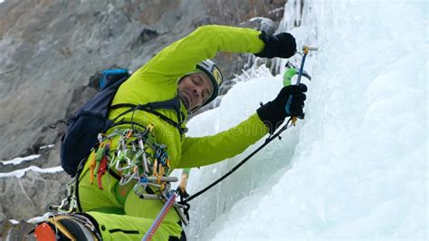 Alpinist Man With Ice Tools Axe Climbing A Frozen Waterfall A Large