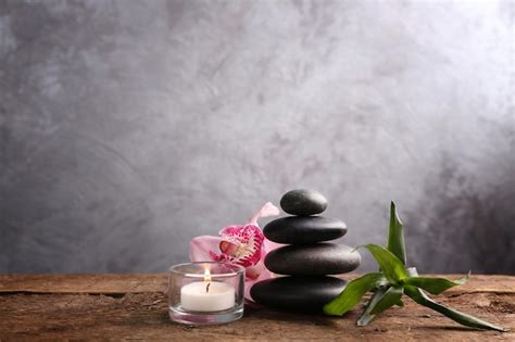 Piedras de spa con orquídeas rosas de bambú y velas sobre una mesa de