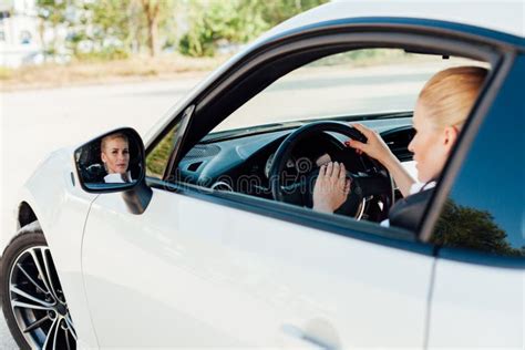 Beautiful Blonde Woman On The Road Driving A White Car Stock Photo