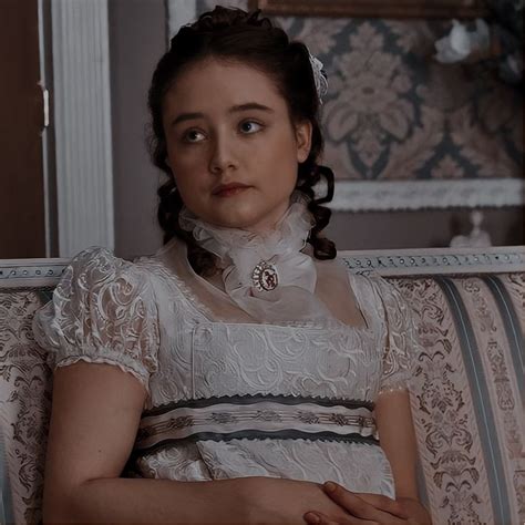 A Woman Sitting On Top Of A Couch Wearing A White Dress And Holding Her