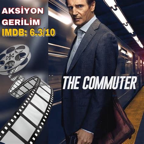 A Man In A Suit And Tie Standing Next To A Movie Poster For The Commuter