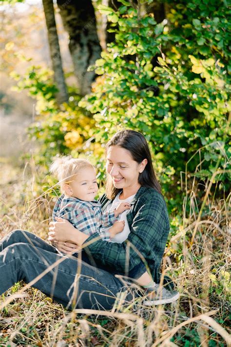 Premium Photo | Smiling little girl sitting on lap of mother embracing