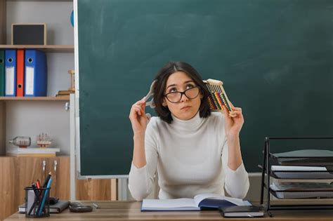 Думающая молодая учительница в очках, держащая счеты с числовым ...