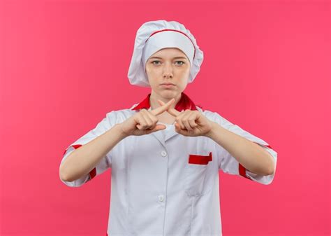 Jeune femme blonde confiante chef en uniforme de chef croise les doigts gestes pas isolé sur mur