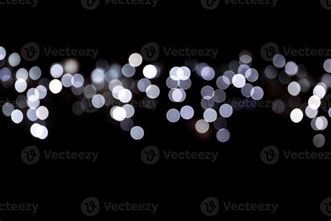 Abstract bokeh of white city lights on black background. defocused and blurred many round light ...