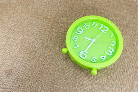 Green Alarm Clock On Brown Sackcloth Background Show Half Eight O Clock