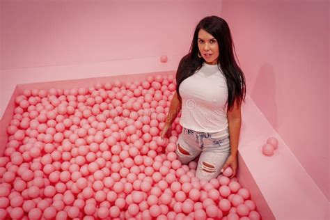 A Lovely Brunette Model Plays In A Room Full Of Plastic Balls Stock