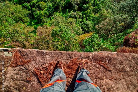 On The Edge Concept With Man Standing On Cliff Ledge Looking Down At