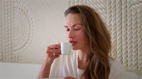 Girl drinking coffee and smiling in bed. 26236688 Stock Video at Vecteezy