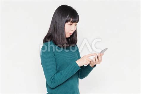 白背景の前でスマホを操作している女性 No 24652535｜写真素材なら「写真ac」無料（フリー）ダウンロードok