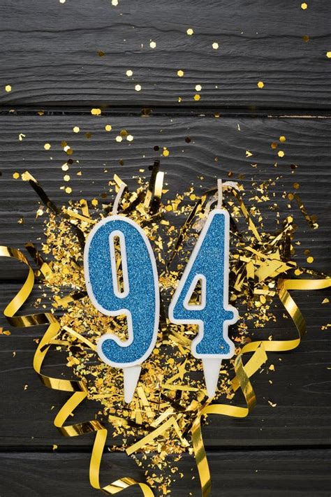 Number 94 Blue Celebration Candle And Gold Confetti On Dark Wooden