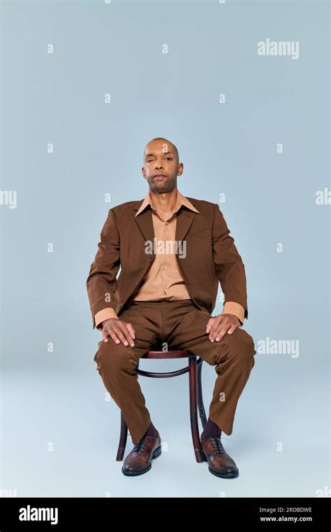 real people, full length of bold african american man with myasthenia gravis sitting on wooden ...