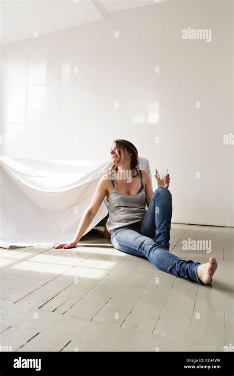 Mature Woman Sitting On Floor In House Pensive Expression Stock Photo Alamy