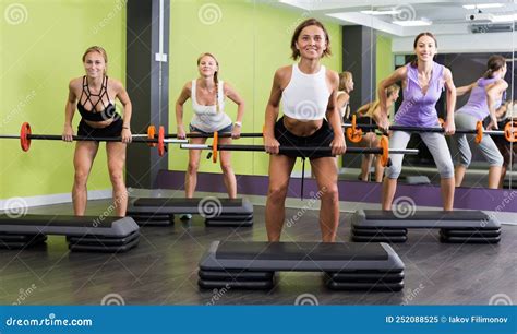 Women Exercising With Barbell Workout At Fitness Club Stock Image