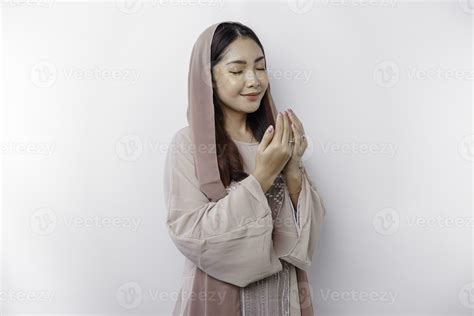 Religious Beautiful Asian Muslim Girl Wearing A Headscarf Praying To God Isolated By White