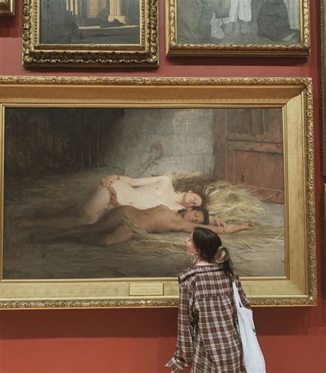 A Woman Looking At Paintings On Display In A Museum