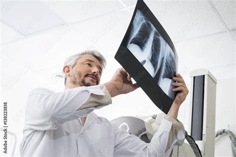 Male Radiologist Analyzing Chest X Ray Report In Examination Roo Photos