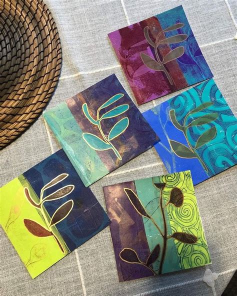 Four Square Paintings On A Table With A Straw Hat And Wicker Basket In