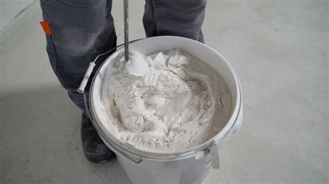 Mixing White Plaster In A Bucket With A Stirrer Close Up White