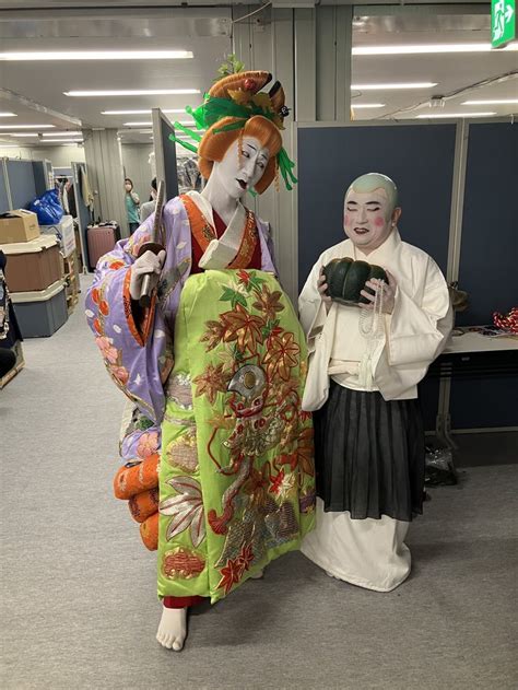 Two People Dressed In Costumes Standing Next To Each Other With Masks