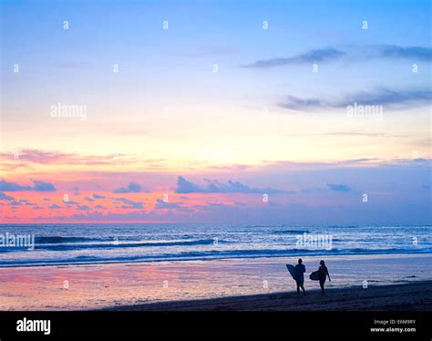 Couple Of Surfers Walking On The Beach On Bali Island Indonesia Stock