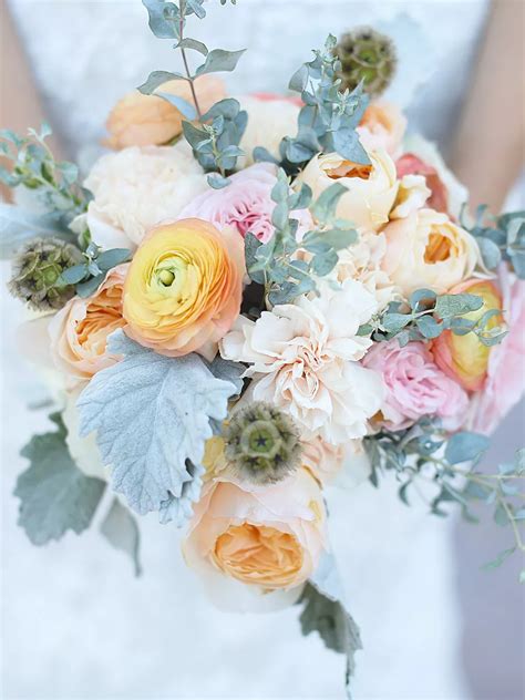 A Bridal Holding A Bouquet Of Flowers And Greenery